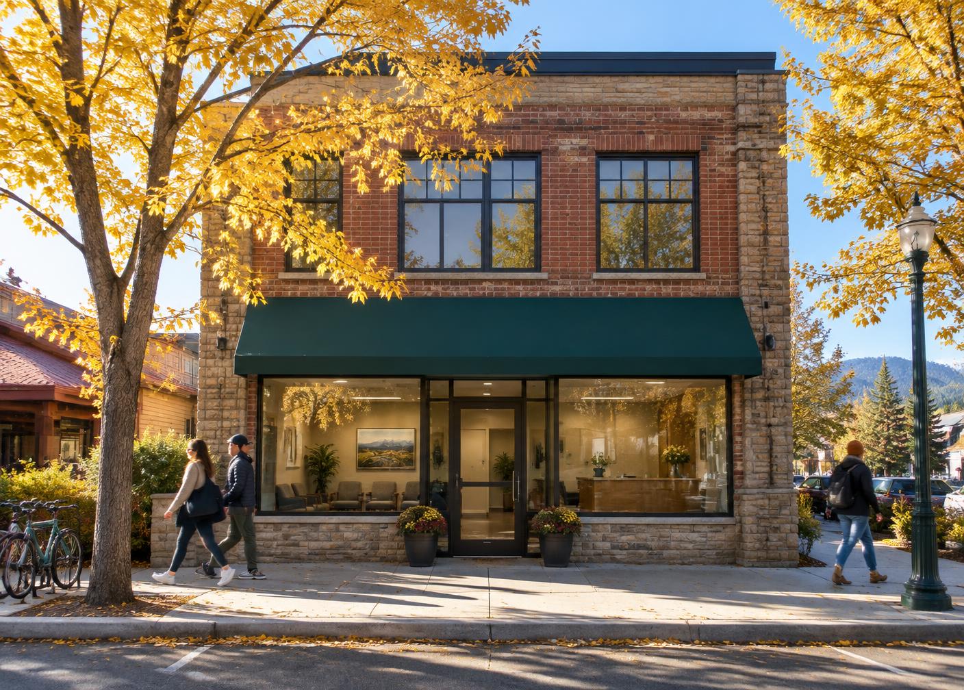 Brick office building with a green awning on a tree-lined Bend street in autumn